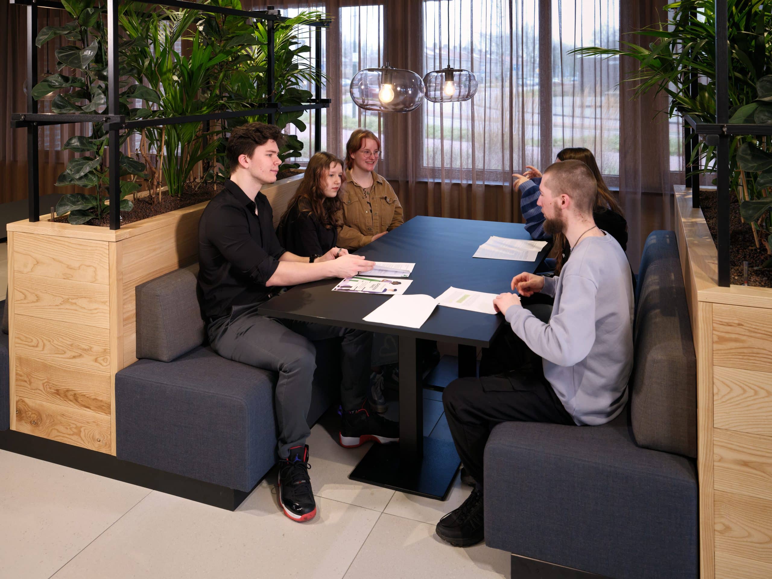 Jongeren die aan tafel zitten aan het werk en discusseren